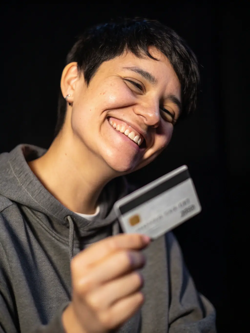 A professional woman smiling while holding a Wamo credit card, showcasing its sleek design and the convenience it offers.
